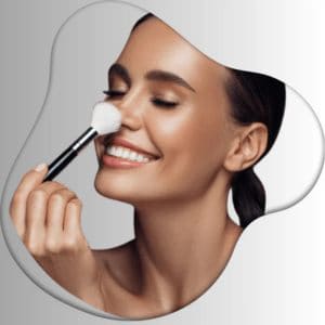 Smiling woman applying makeup with a soft brush on nose against gray background