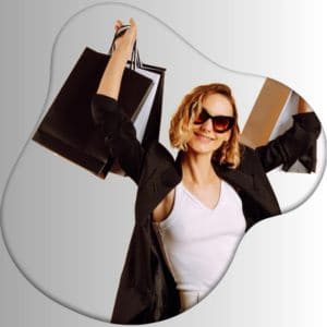 Happy young woman in sunglasses holding multiple black and brown shopping bags against white and gray background